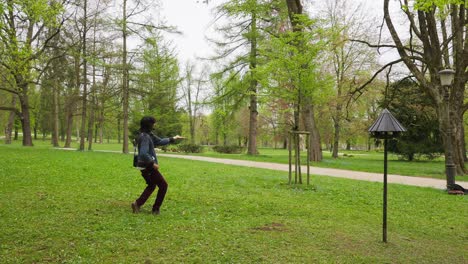 slow motion shot of a young man holding out his hand with nuts to attract a bird