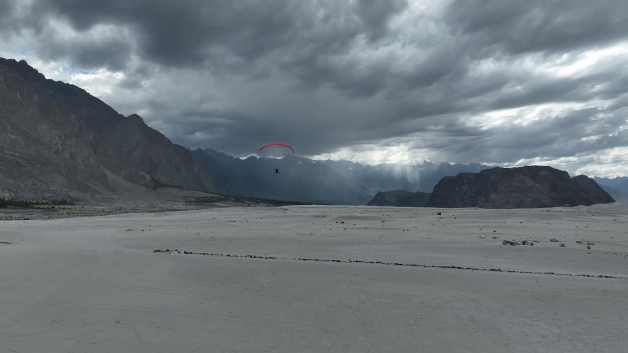 vista aérea de un parapente volando sobre el desierto de sarfaranga con nubes nubladas dramáticas
