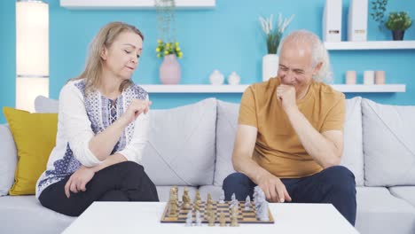 married couple playing chess at home.