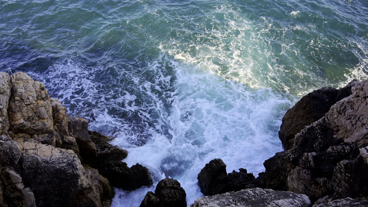 The waves of the Mediterranean Sea crashing on the rocks on the shore of the French Riviera