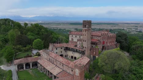 cerrando la antena que se aleja del castillo de camino y las montañas circundantes y el campo en piamonte, italia