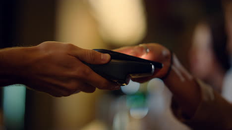 visitor hand paying with mobile phone indoors. hand giving terminal for payment.