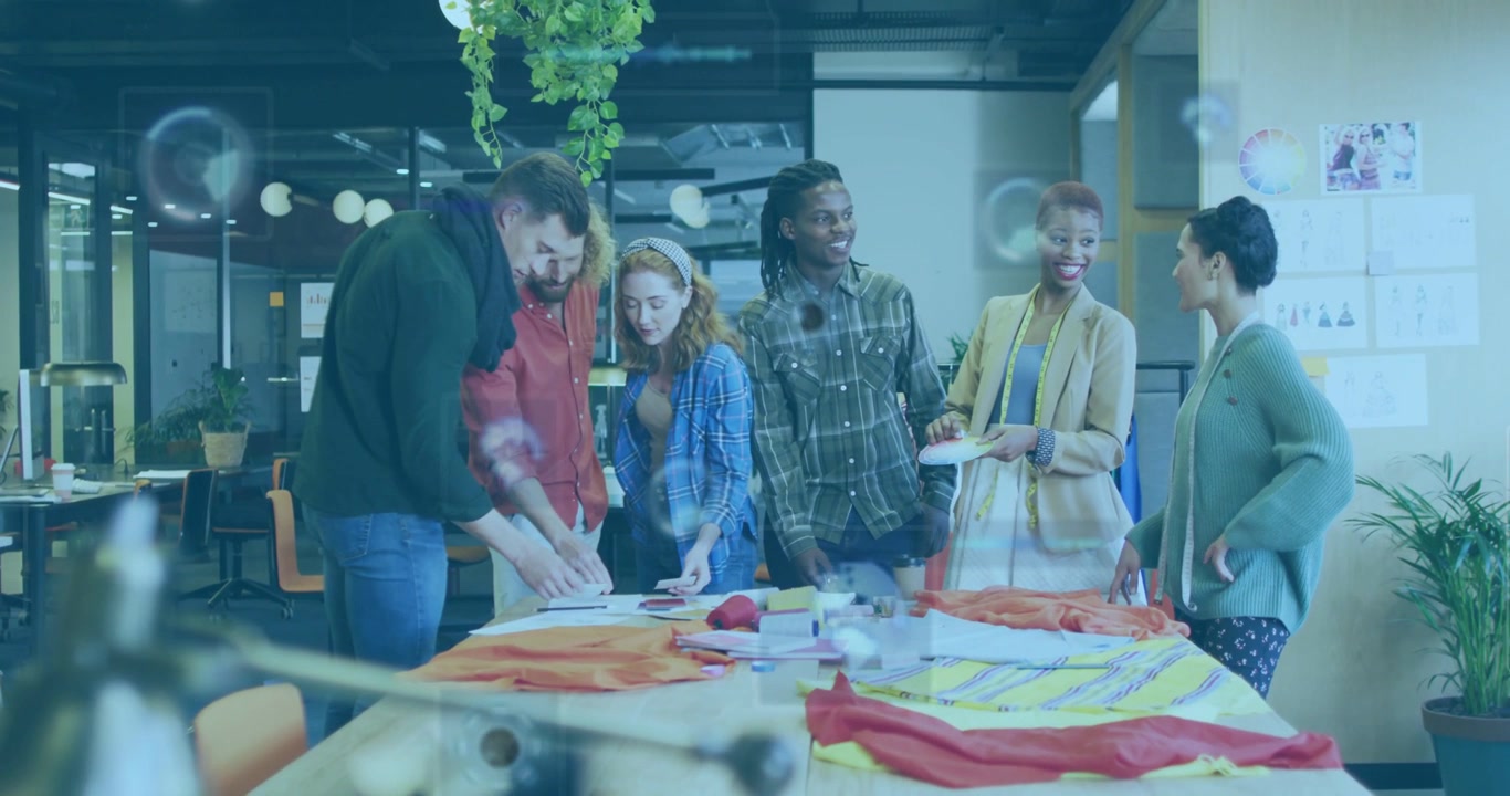 Design team leaning around table, tall man pointing, starting swatch review with HUD marking picks