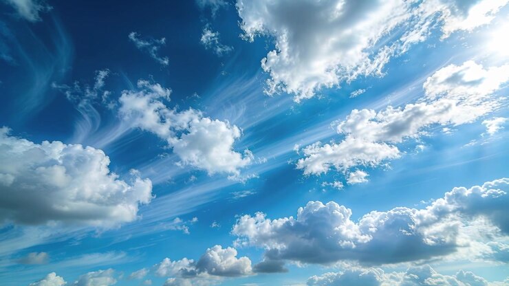Nubes cúmulos y cirros a la deriva cruzando el cielo azul, la luz del sol produciendo un resplandor de contraluz