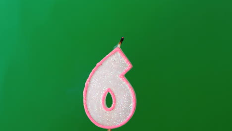 Six-birthday-candle-flickering-and-extinguishing-on-green-background