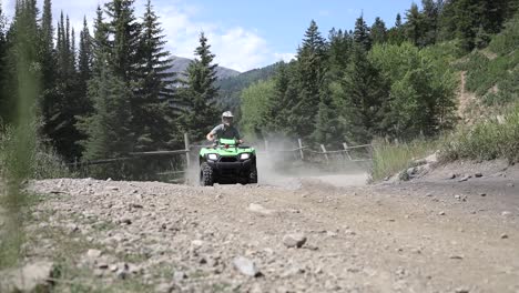 shot of an atv rider driving his quad really fast around a corner, leaving a large dirt cloud behind him