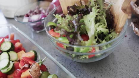 Close-up-of-chopped-vegetables-and-salad-on-worktop-in-kitchen,-slow-motion
