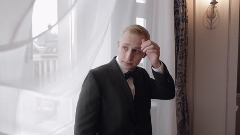 el novio se prepara con traje y corbata de papagaio.