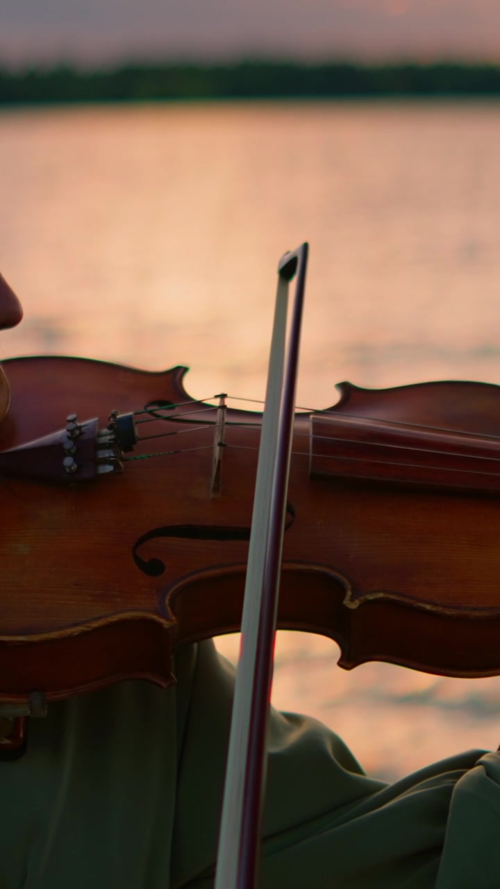 Woman Playing Violin by the Lake at Sunset