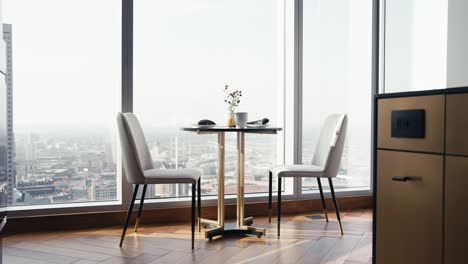 a small table set with 2 chairs in a luxury condo next to large windows overlooking the city