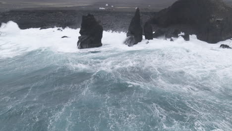 fotografía aérea de las olas de la costa de islandia a través de los acantilados y la gente mirando el horizonte en un día nublado