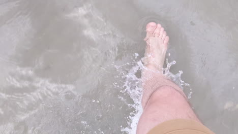 man barefoot in shorts walks in the clear shallow salt lake water in utah