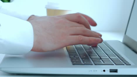 a man in a white shirt is working at a laptop. close-up