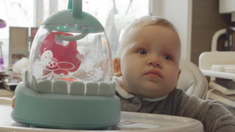 baby girl on highchair with a toy