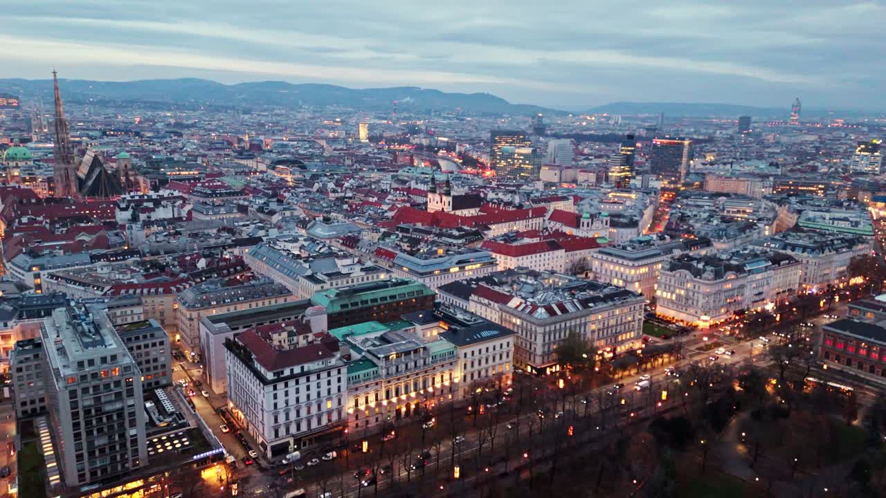 Ripresa aerea statica con drone del paesaggio urbano di Vienna di notte in inverno, che mostra edifici illuminati, strade illuminate, traffico scorrevole e luci della città che si riflettono sui tetti sotto il cielo invernale