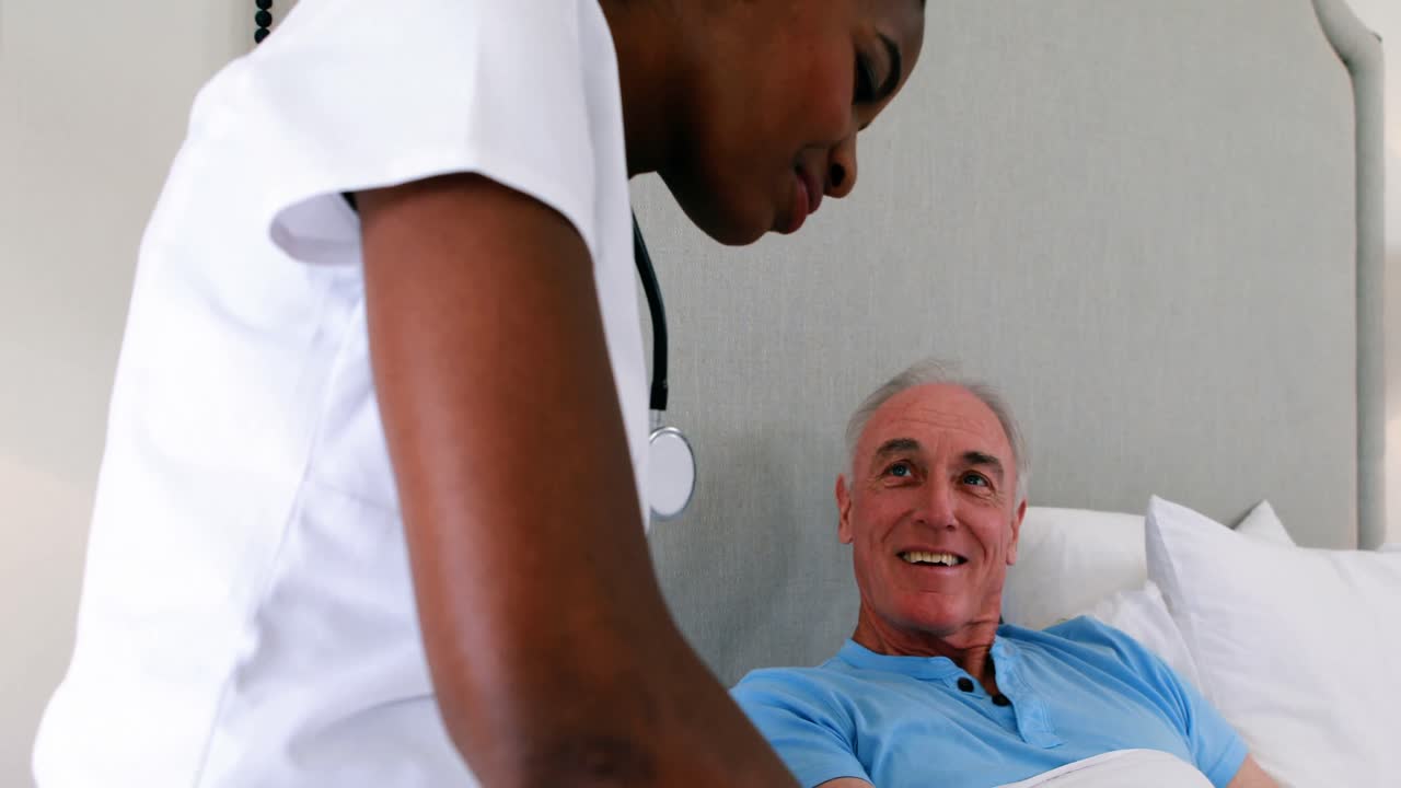 Krankenschwester untersucht älteren Mann im Bett