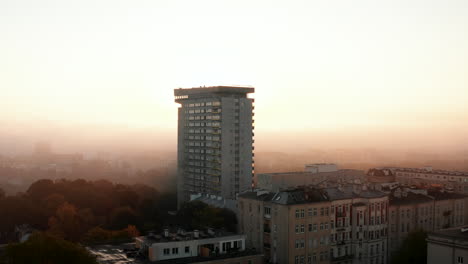 Slide-and-pan-footage-of-Mlotek-apartment-high-rise-building.-Tall-prefab-against-sun-rising-behind-fog.-Warsaw,-Poland