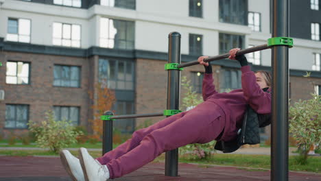 exercise lover performing press up on horizontal rod in urban park. focus on strength training and outdoor fitness routine, demonstrates determination and athleticism in urban park setting