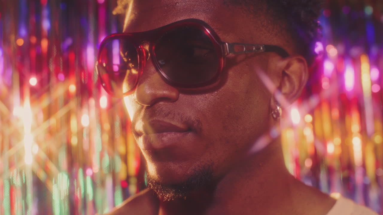 Close Up of Black Man in Stylish Sunglasses under Multicolored Lights