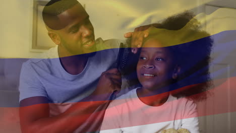 animation of flag of colombia over african american father with daughter