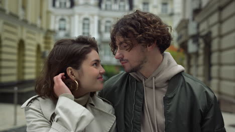 Happy-couple-looking-eyes-to-eyes-on-urban-street.-Man-kissing-woman-forehead.