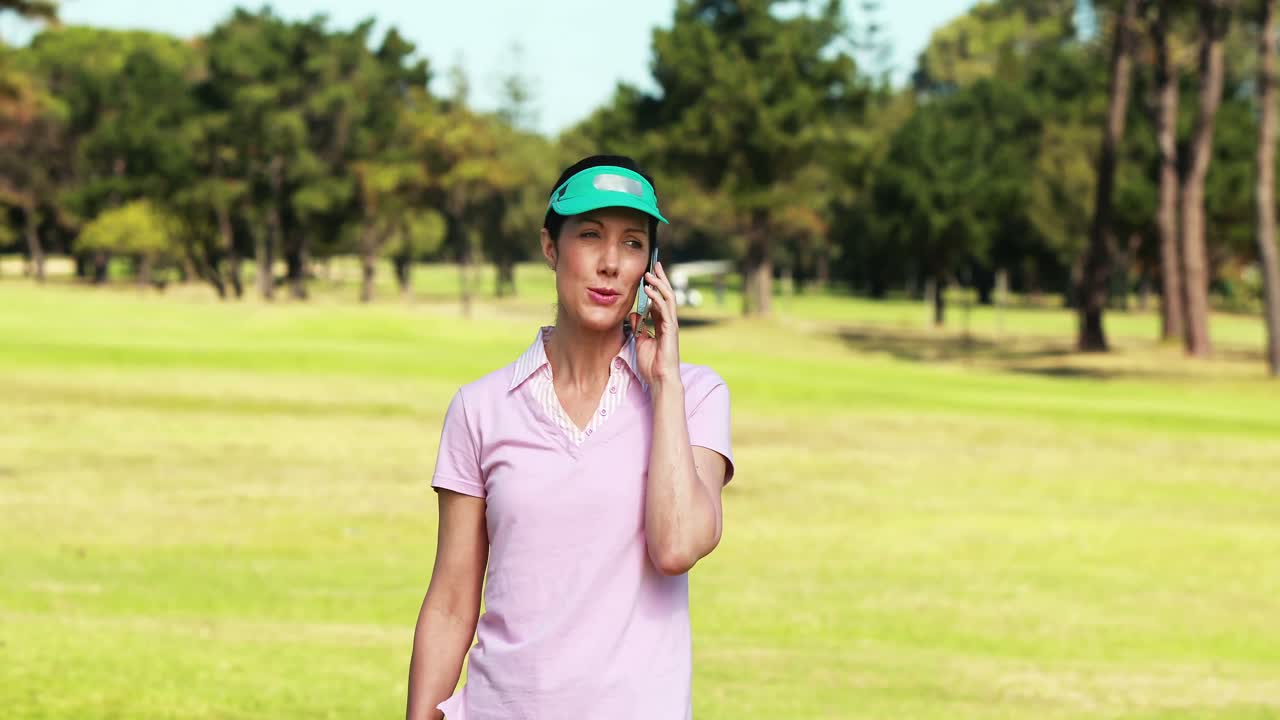여자 골프 선수 가 골프 를 치는 동안 휴대 전화 로 이야기 하고 있다
