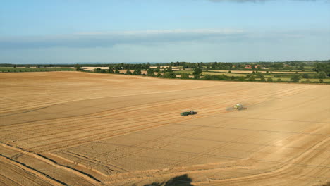 zooming establishing drone shot of combine harvester and tractor with trailer with power lines in the foreground at golden hour uk