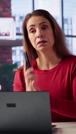 vertical video mature woman getting angry and yelling on the phone call at the desk