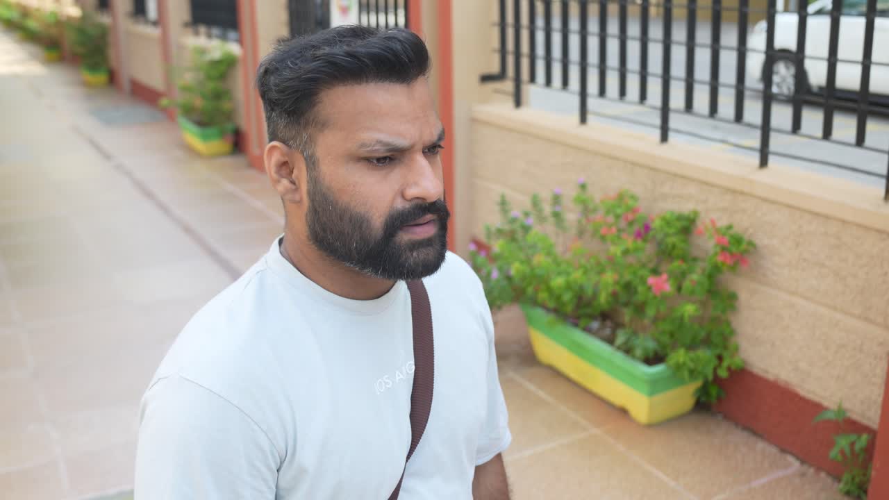 Portrait of a young man checking out his watch as he is waiting for someone on the sidewalk