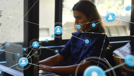 animation of network of digital icons over woman using laptop