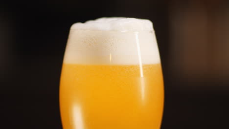 close up of craft beer being poured in to a goblet beer glass, dark background