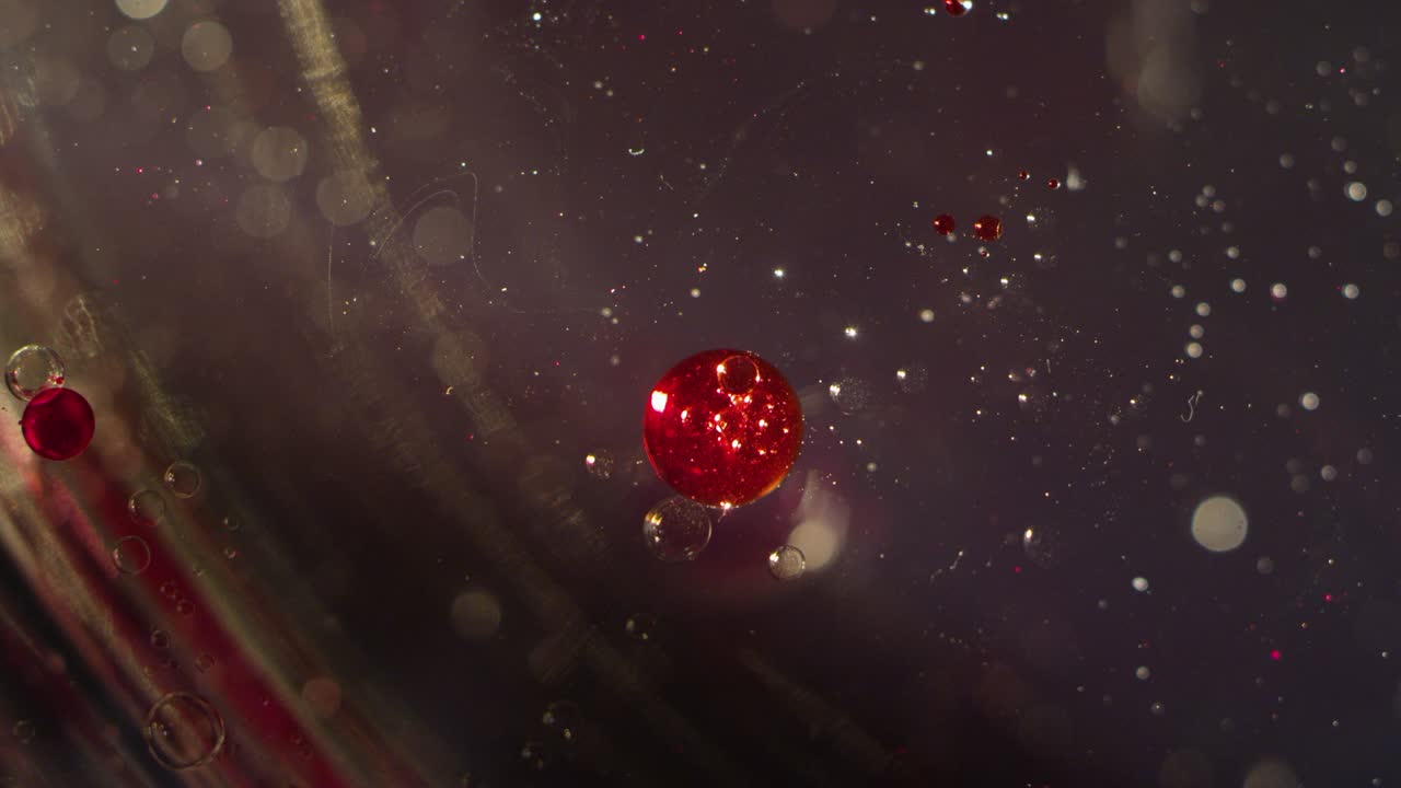 два абстрактных красных плавающих блестящих блестящихся шара преображаются вместе на прозрачной жидкой текстуре фона боке