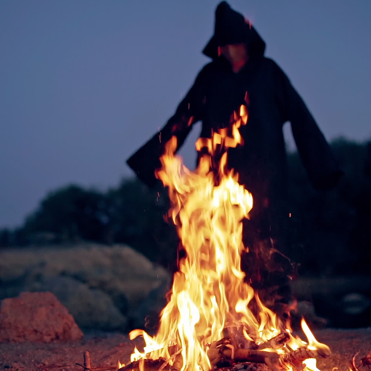 Old evil witch by fire in night forest. Scary Halloween concept