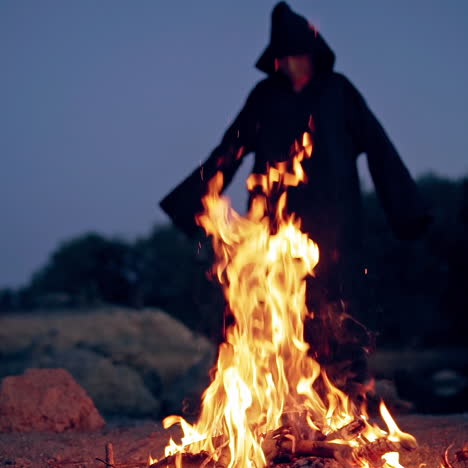 old evil witch by fire in night forest. scary halloween concept