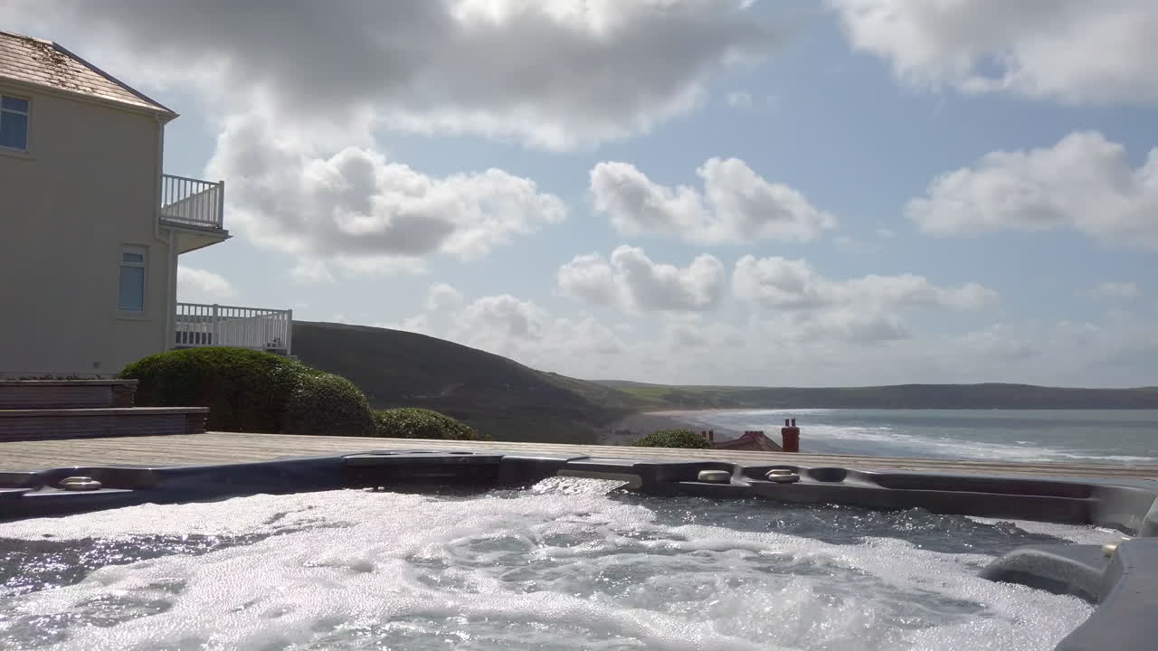 제트기가 실행되고 해변을 배경으로 하는 온수 욕조의 왼쪽에서 오른쪽 샷
