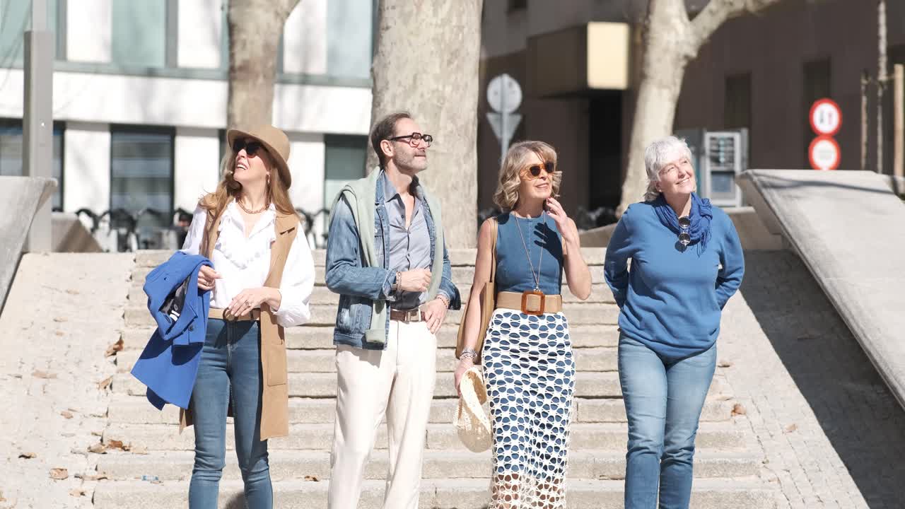 Stylish mature friends walking down stairs on street