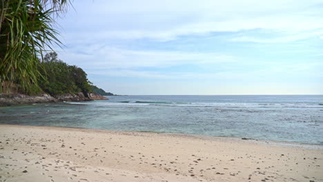 vista a la playa de la isla tropical con un exuberante paisaje verde al lado de una playa de arena y un océano azul claro
