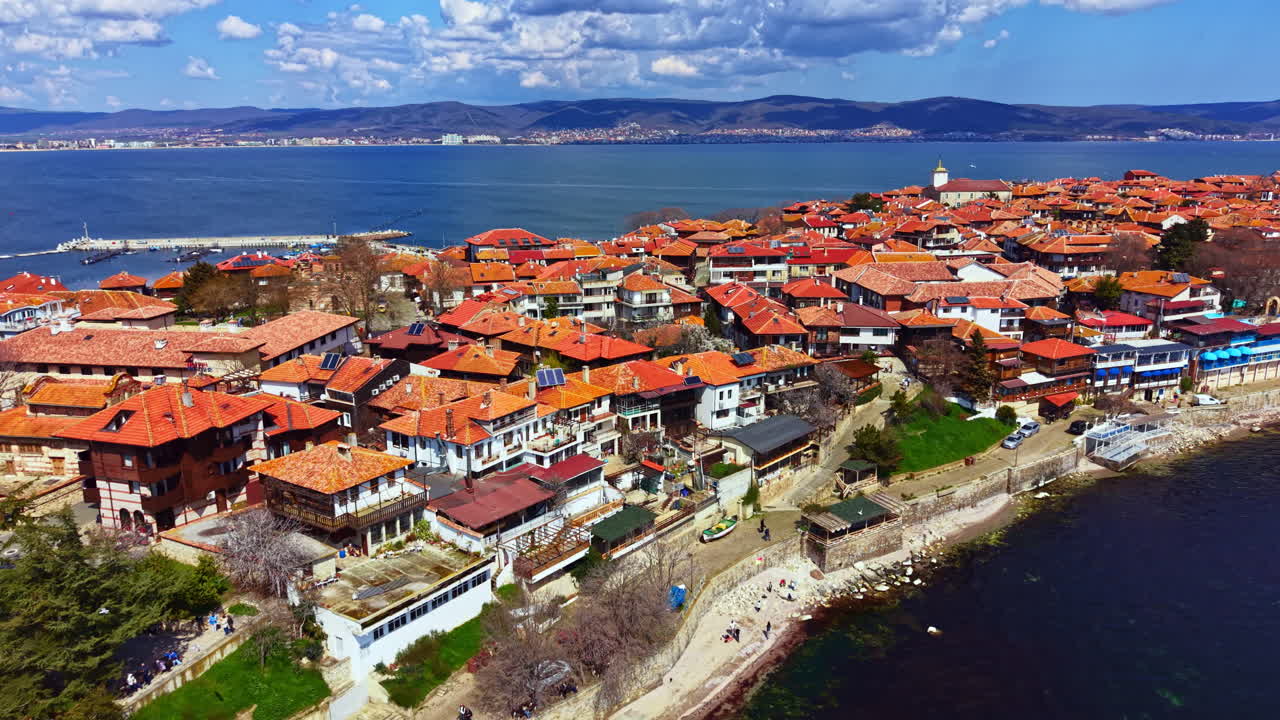 Nesebar Eski Kenti, gündüz vakti Karadeniz kıyısında turuncu çatılı ve sakin sularıyla kıyı mimarisini sergiliyor.