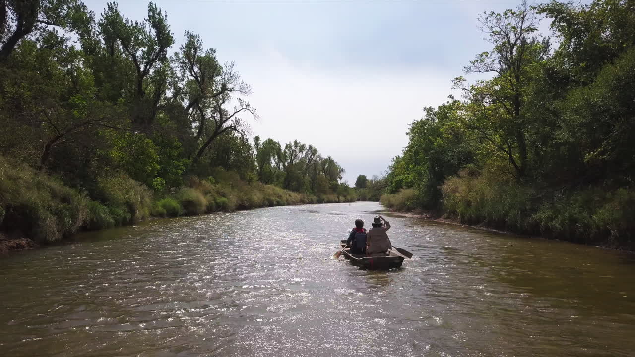 Carrellata aerea lenta di una famiglia che pagaia risalendo un fiume fangoso in Georgia.