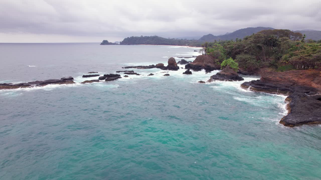 Stormy waves crash on Praia Piscina, São Tomé, a dramatic blend of wild ocean power and serene tropical beach landscape