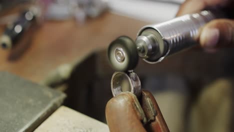 biracial female worker shaping ring using handcraft tools in workshop in slow motion