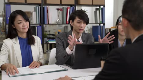 selective focus asian startup male manager of sales team talking with hand gesture while trying to sell services to important customer at meeting