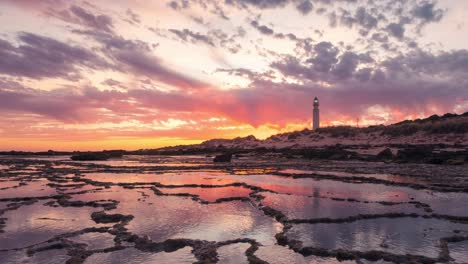 Hermosa-Puesta-De-Sol-Timelapse-En-El-Faro-De-Trafalgar-Con-Primer-Plano-De-Patrón-Rocoso-Y-Pequeños-Estanques-De-Agua