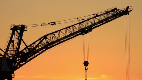 silhouette of a towering crane against a stunning sunset skyline, showcasing the intricate structure and mechanisms of heavy construction equipment