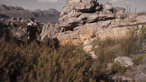 Man-is-hiking-in-the-nature,-rocky-mountains-are-visible-in-background