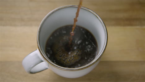 150fps slow motion wide black coffee pours into a cup, splashing