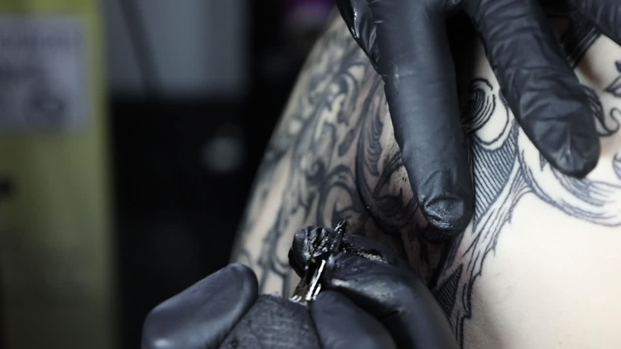 Tattoo artist uses machine, needle applies black ink for intricate handcrafted design on skin, focus on precision, artisan skill, body art process. Extreme close-up macro shot