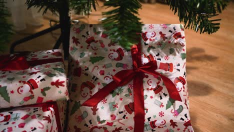 Shot-of-wrapped-little-presents-under-a-decorated-plastic-Christmas-tree-in-the-house,-panning-shot