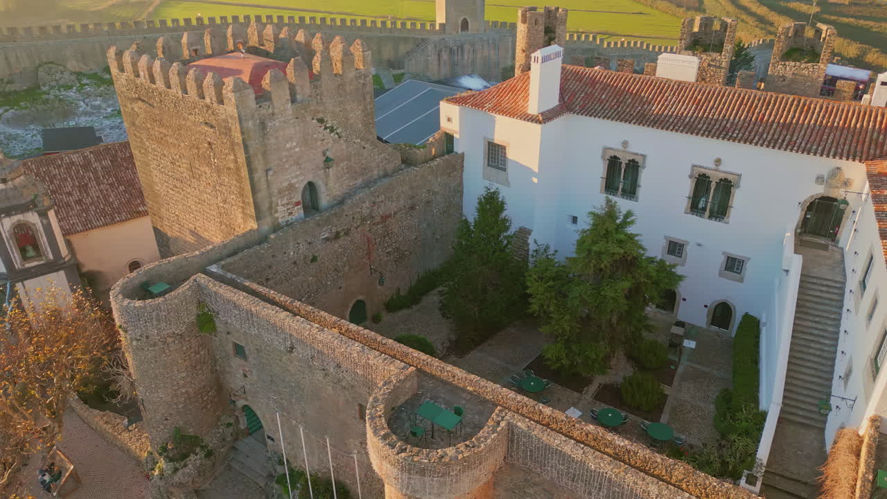 Monumental stone castle towering over small town drone view. Medieval walls