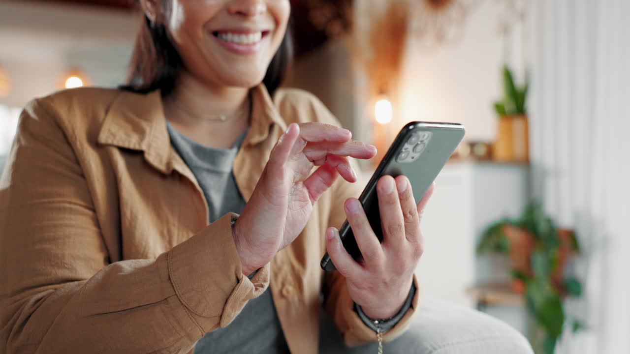 mujer sonriendo mientras usa su teléfono en casa
